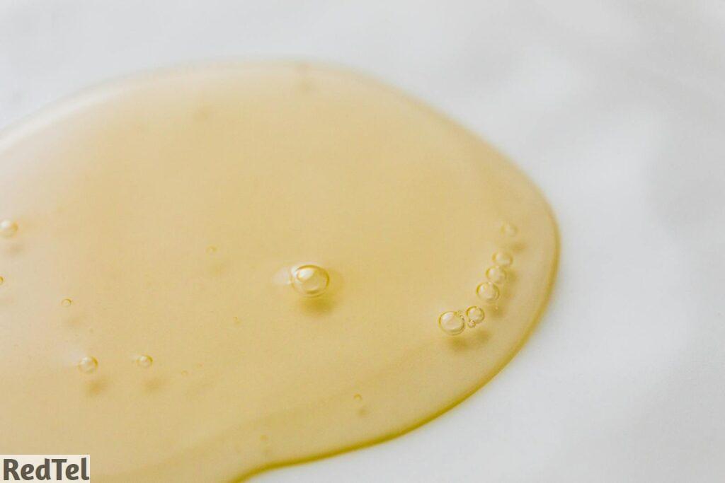 Close-up of a golden liquid with bubbles on a white surface, showcasing beauty and purity.